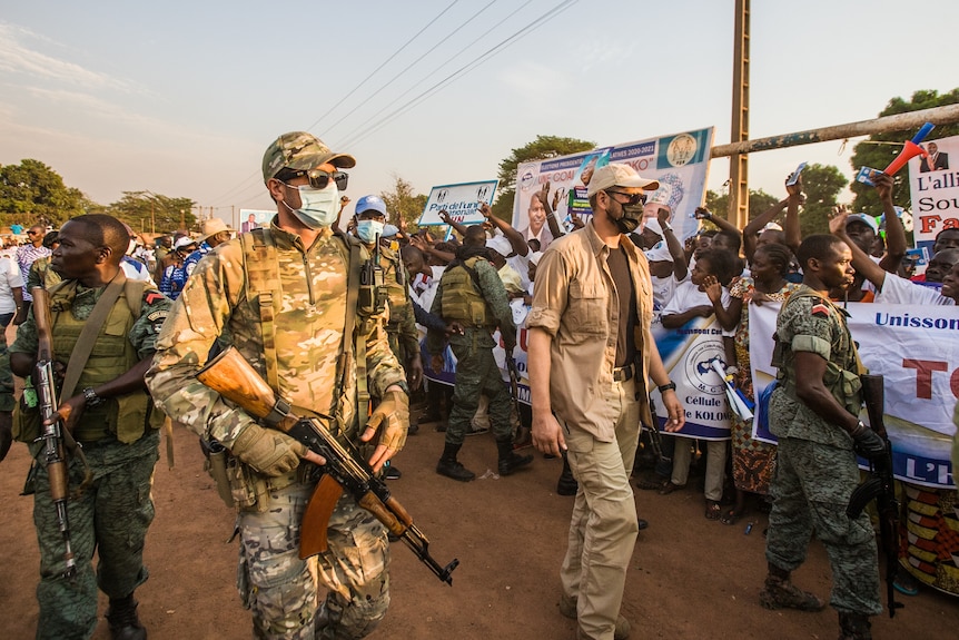 Russian and Rwandan soldiers walk near a protest in Africa