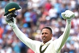 Usman Khawaja raises his hands and helmet in celebration of an Ashes century.
