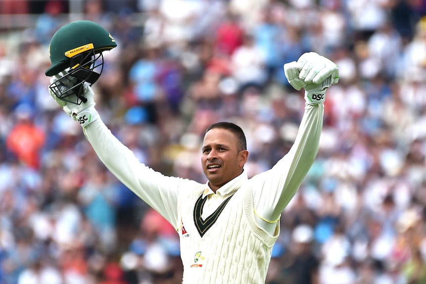 Usman Khawaja raises his hands and helmet in celebration of an Ashes century.