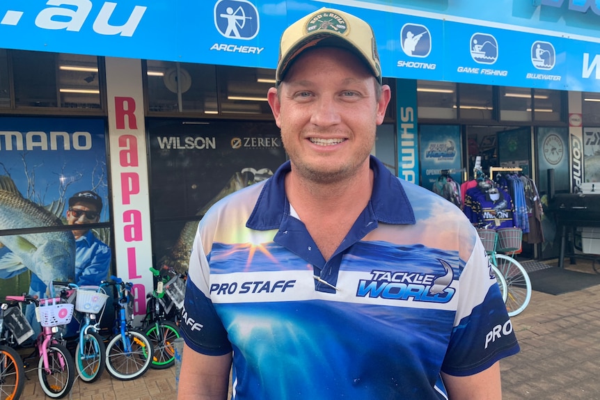 A man in a cap and fishing shirt outside a shop with bicycles at the front