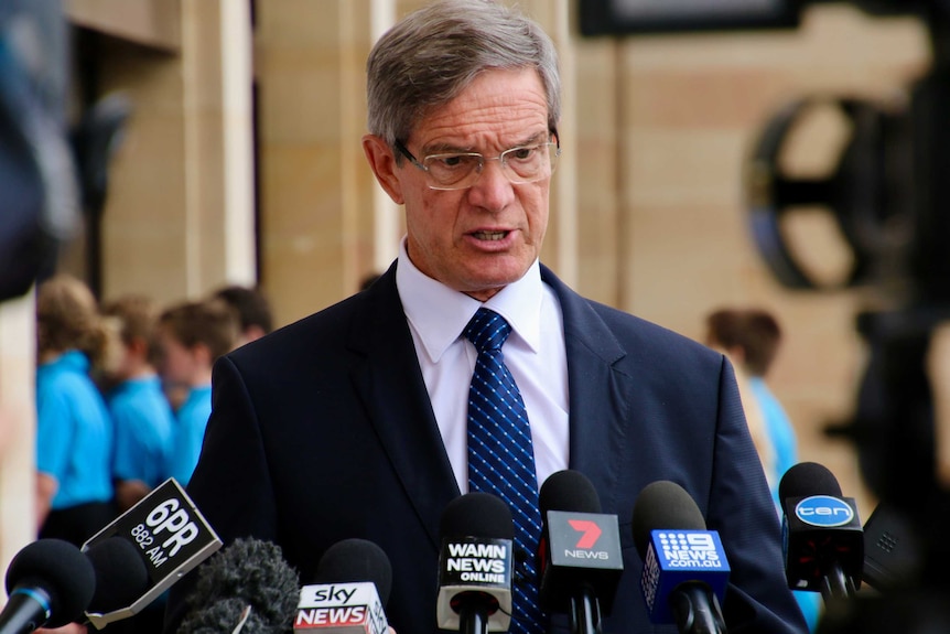 A mid-shot of WA Opposition Leader Mike Nahan standing outside State Parliament in a suit talking to reporters.