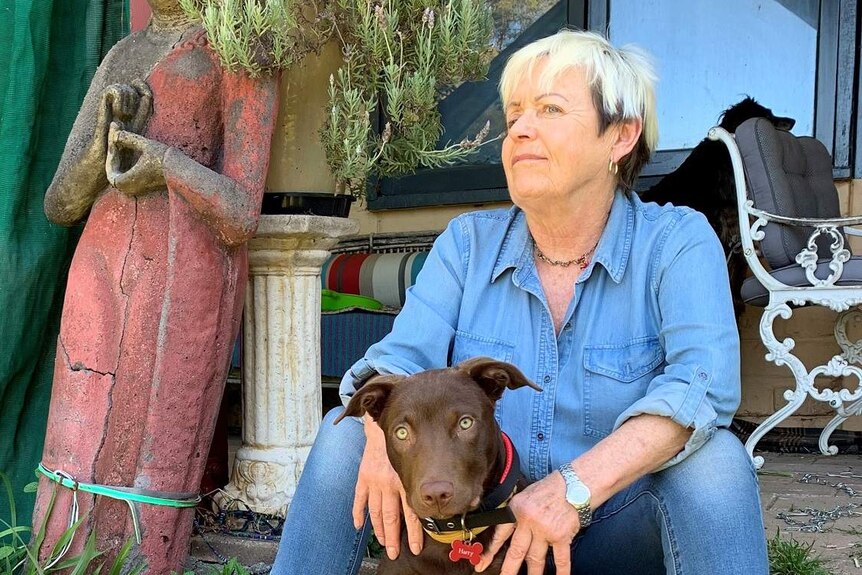 Angela Davison sits on a step in fron of her home with her dog.