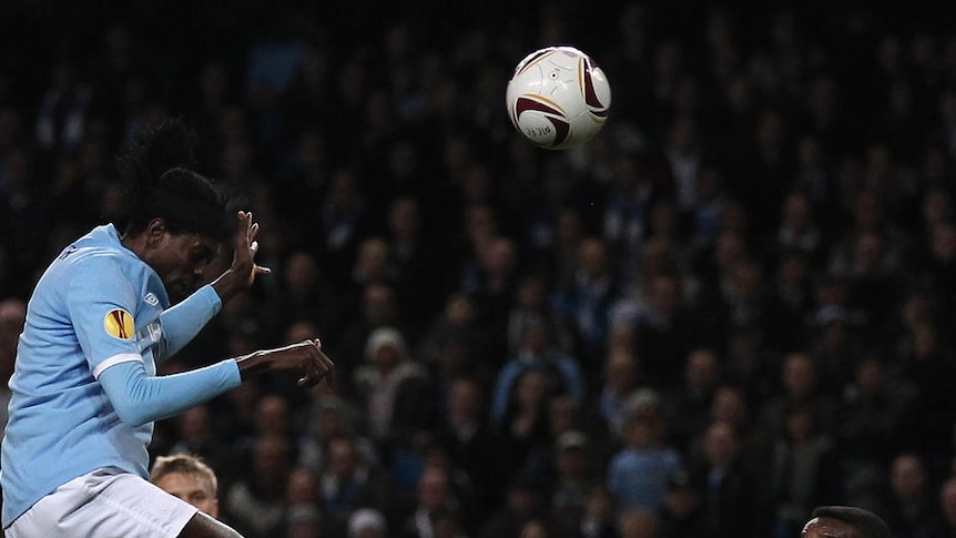 Three goals to the good: Emmanuel Adebayor rises high to nod home his second en route to a trebel.