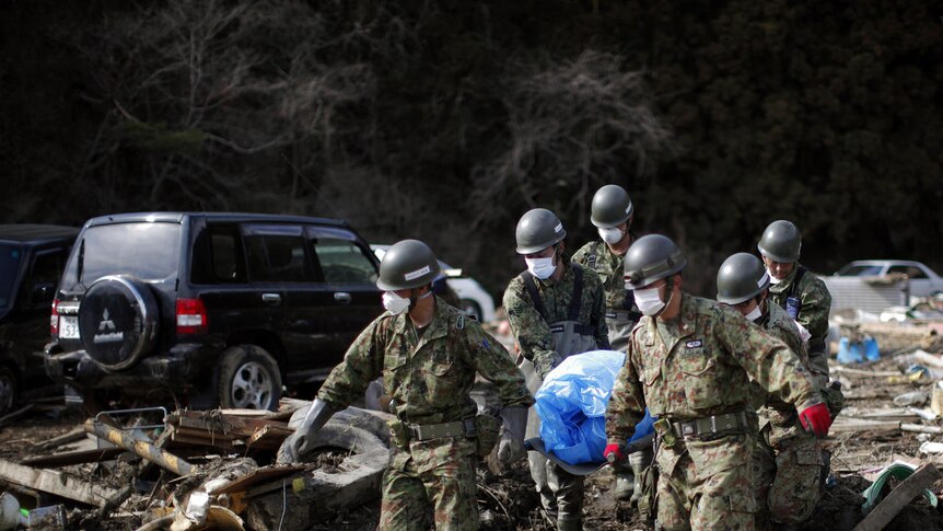 Members of Japan's self-defence force carry a body out of the rubble