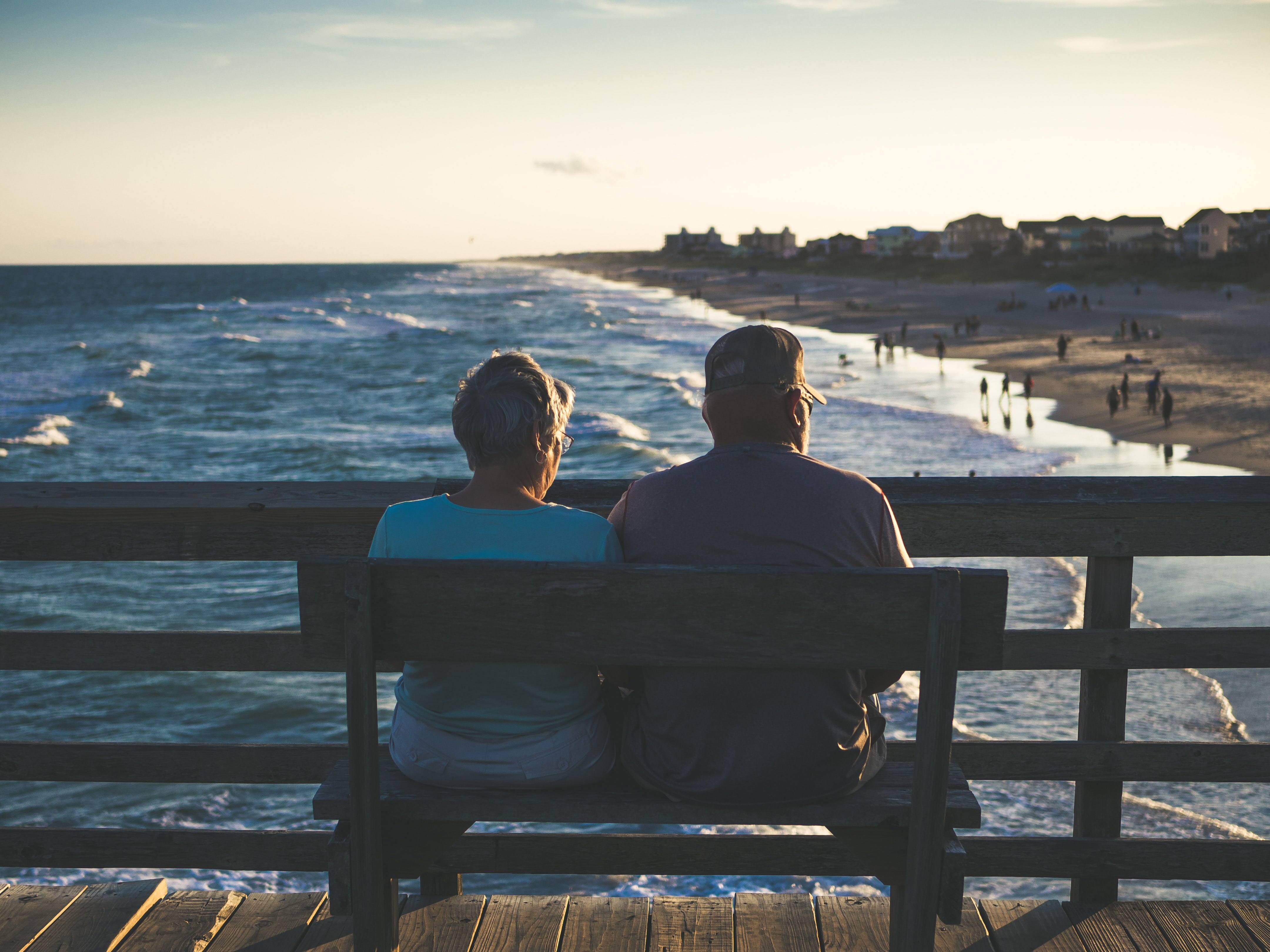 Older couple sitting on a bench overlooking a beach in the golden light.