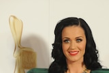 Singer Katy Perry in an emerald green dress, standing in front of a gold logie
