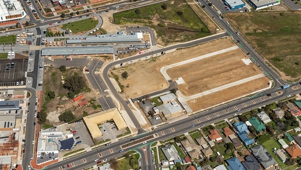 An aerial view of a patch of undeveloped land, surrounded by roads and houses