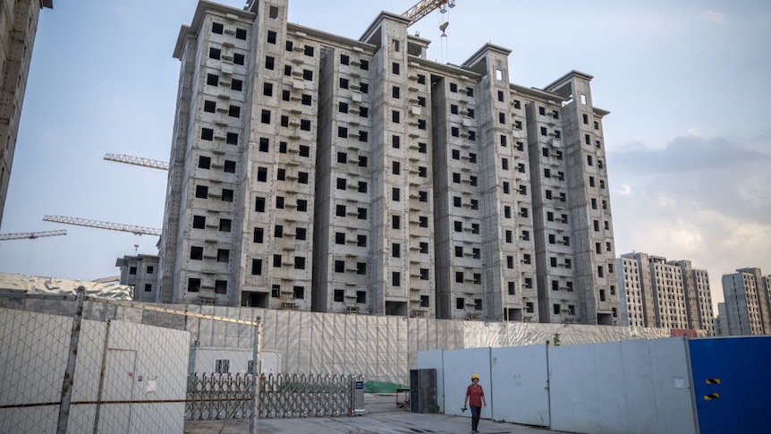 A worker leaves a building site of an unfinished  multi story residential block 