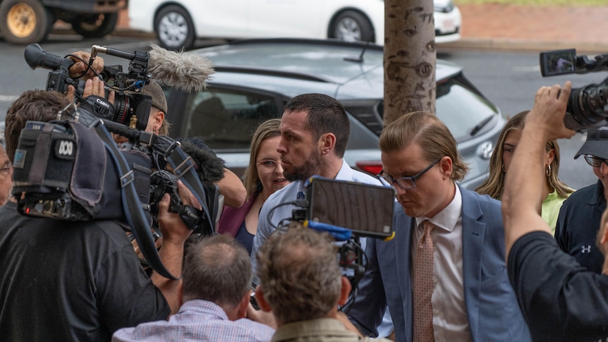 A man surrounded by people and TV cameras. 