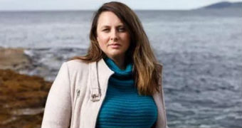 Angela Williamson stands in front of an ocean