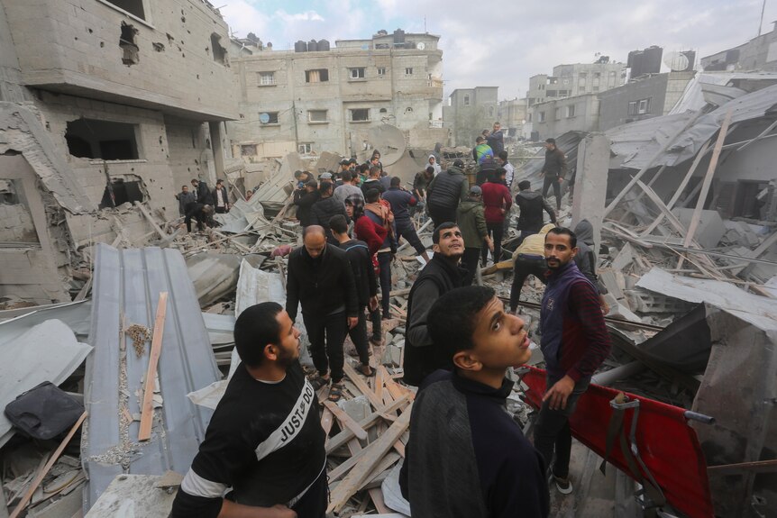People crowd around building rubble looking for survivors 