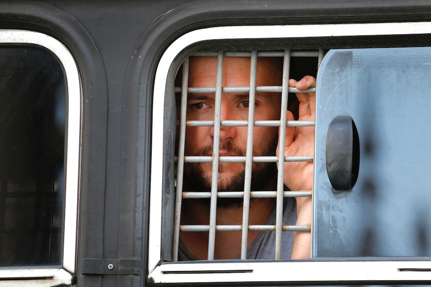 A detained protester looks out of a police bus window.