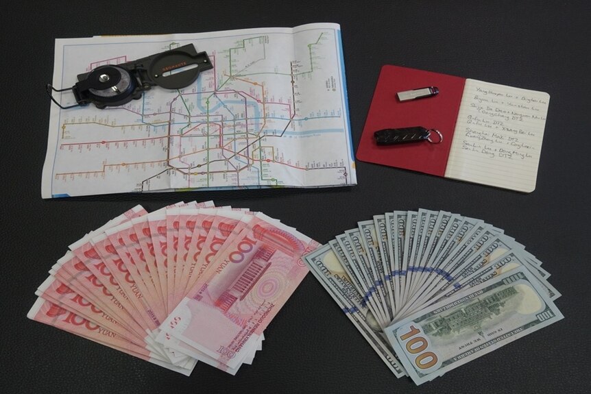 A map of Shanghai's train system, a compass, a notebook, USB stick and cash in US and Chinese currency.