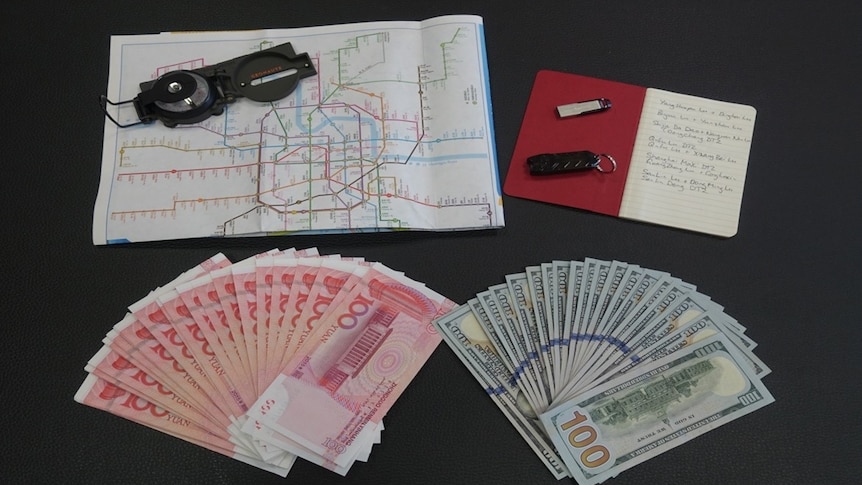 A map of Shanghai's train system, a compass, a notebook, USB stick and cash in US and Chinese currency.