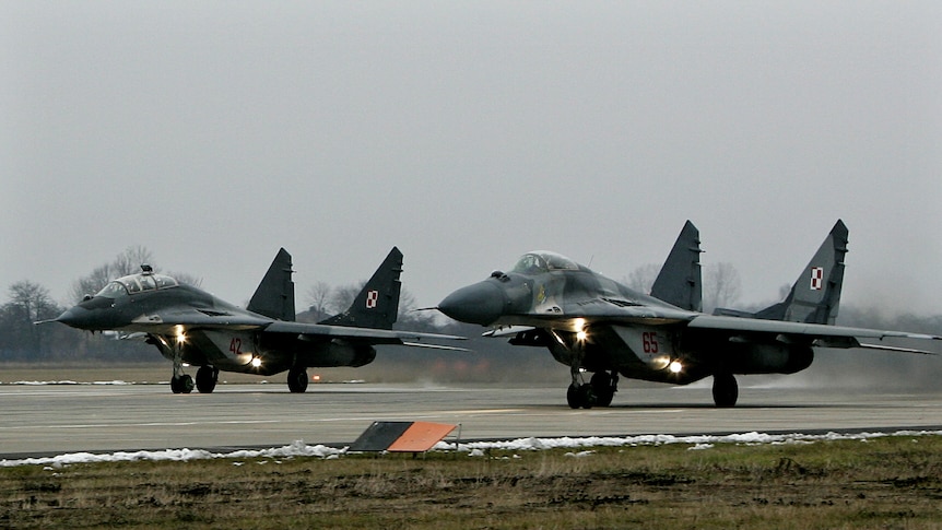 Two dark strike jets lift noses off the runway as they launch into flight for a mission.