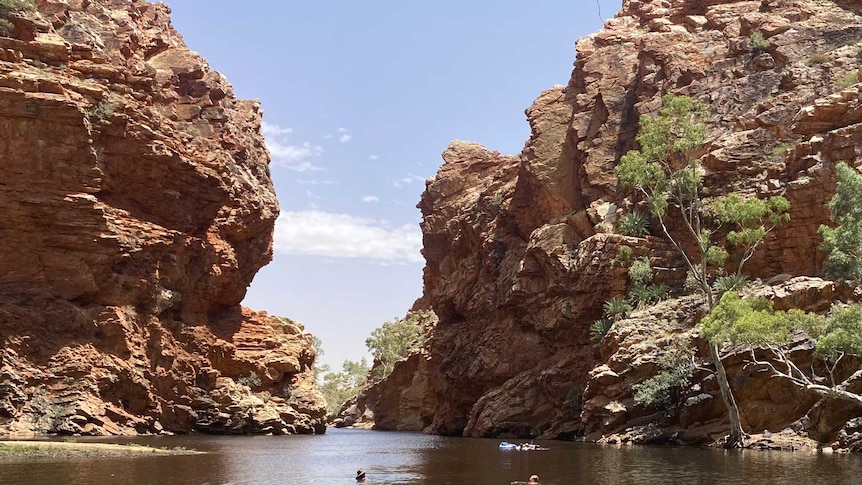 Swimmers at a spectacular waterway bordered with stunning rock formations in the NT.