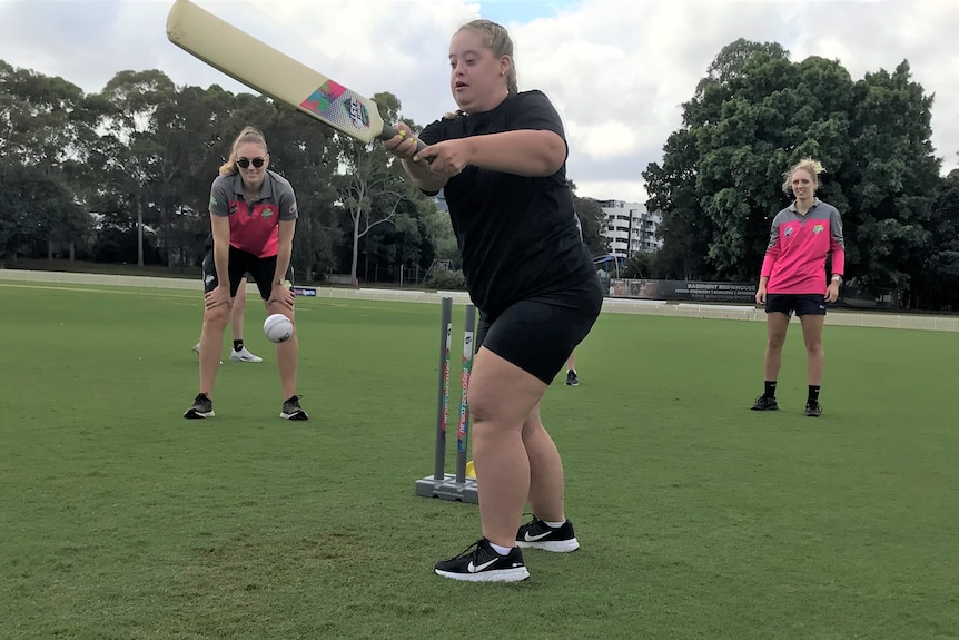 A girl hits a cricket ball