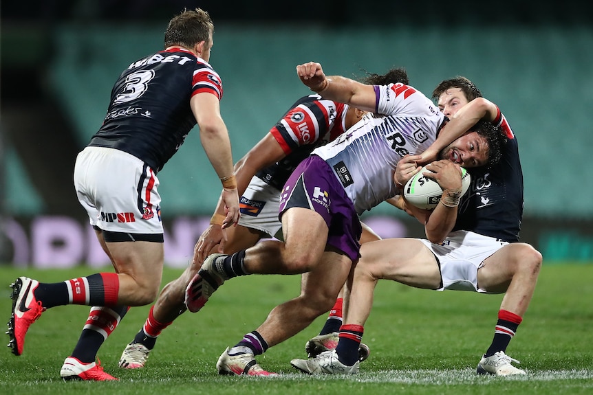 Melbourne Storm player Brandon Smith getting tackle by three Sydney Roosters player during a match
