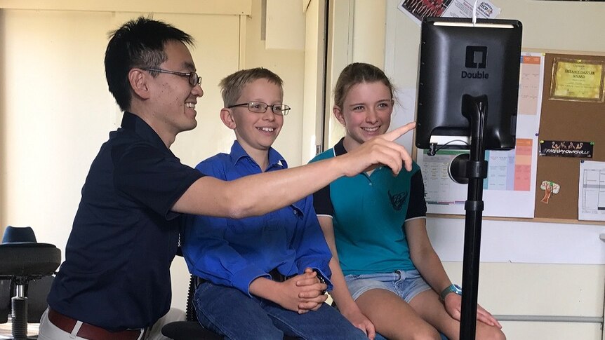 Manager Husao Yoshioka showing Tom and Lana Ramsay how to use robot teacher