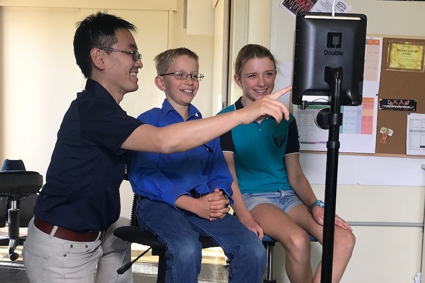 Manager Husao Yoshioka showing Tom and Lana Ramsay how to use robot teacher