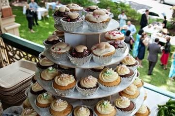A tiered tray of cupcakes sitting on a table at a wedding