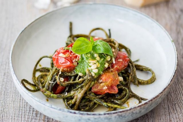 Plate of seaweed pasta with whole tomatoes and basil