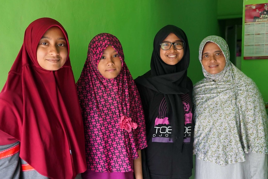 Nur Dhania smiles for the camera in the arms of her mother and sisters