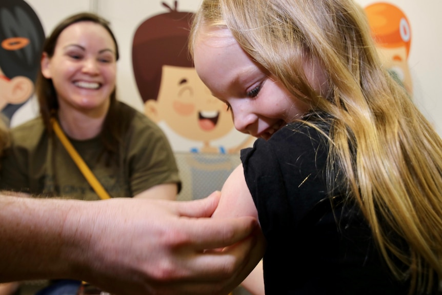 Imogen Morris, 8, smiles as she gets her first COVID vaccination.