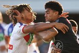 A Wests Tigers NRL player carries the ball as he is tackled by a Newcastle Knights opponent.