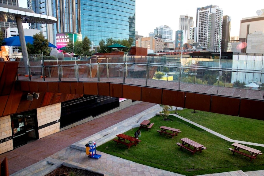 A bird's eye view of a woman cleaning a picnic bench in Yagan Square in Perth.