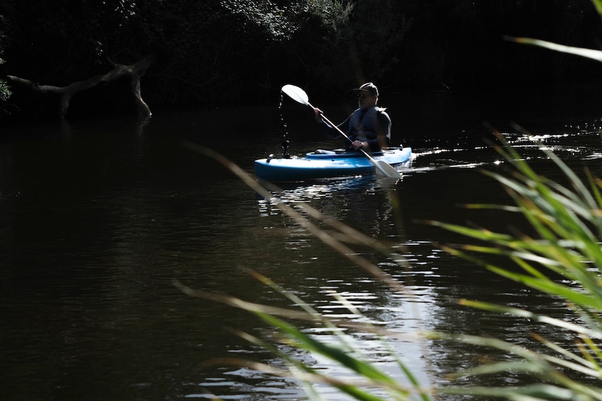 A man rowing a kayak down a river.