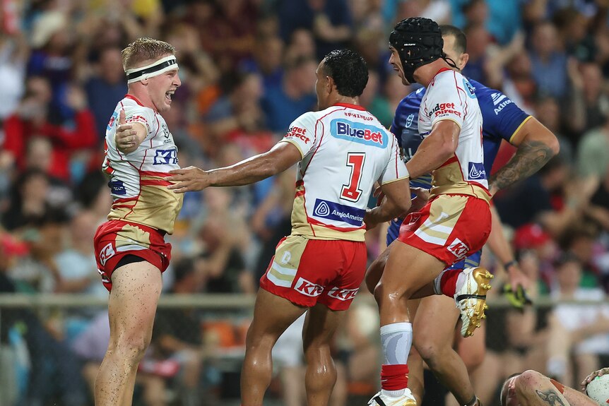 A rugby league player celebrates a try with his teammates 