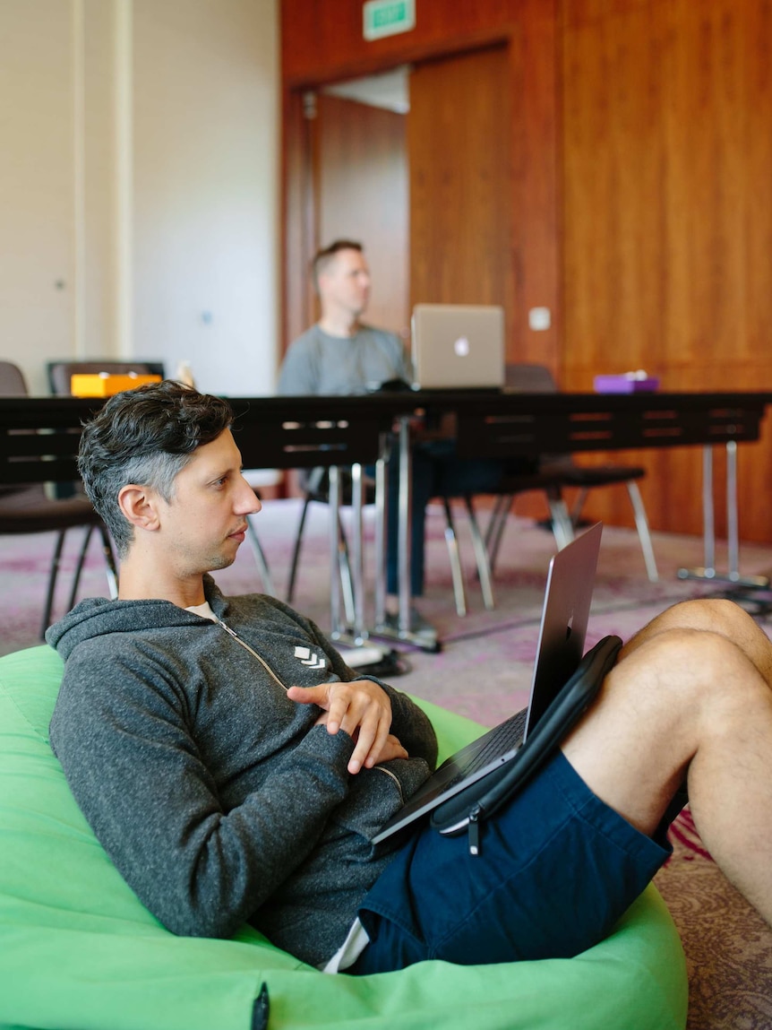 A youngish worker on a laptop on a beanbag