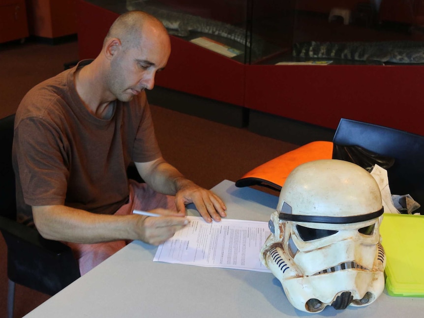 Scott Loxley fills out the paperwork ahead of his underwater encounter with a saltwater crocodile in Darwin.