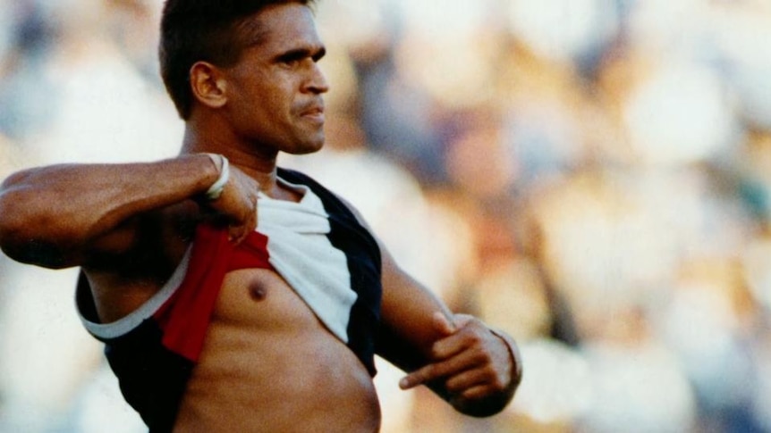 Footballer Nicky Winmar lifts football guernsey and points to his own skin