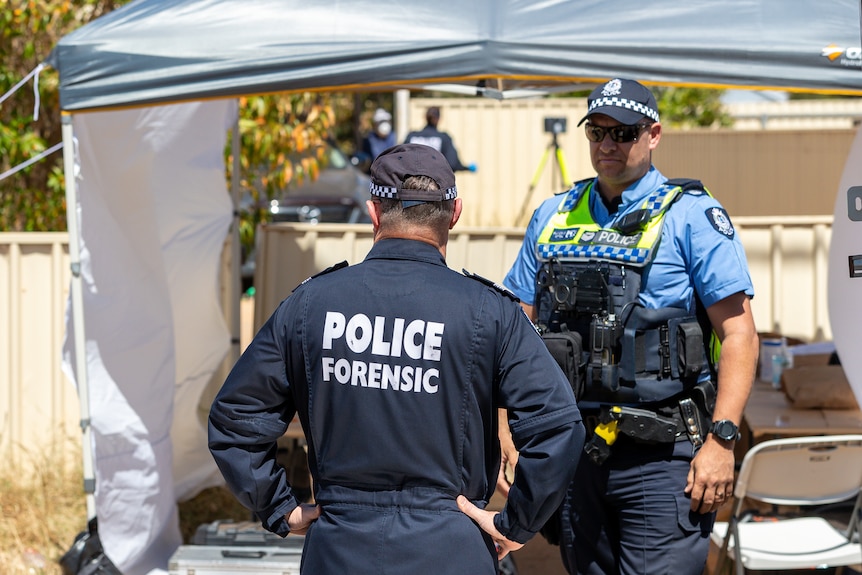 A forensics officer pictured from behind with a policeman at a crime scene