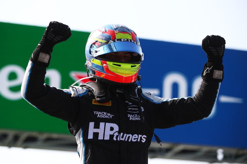 Racing driver raises his arms in victory.