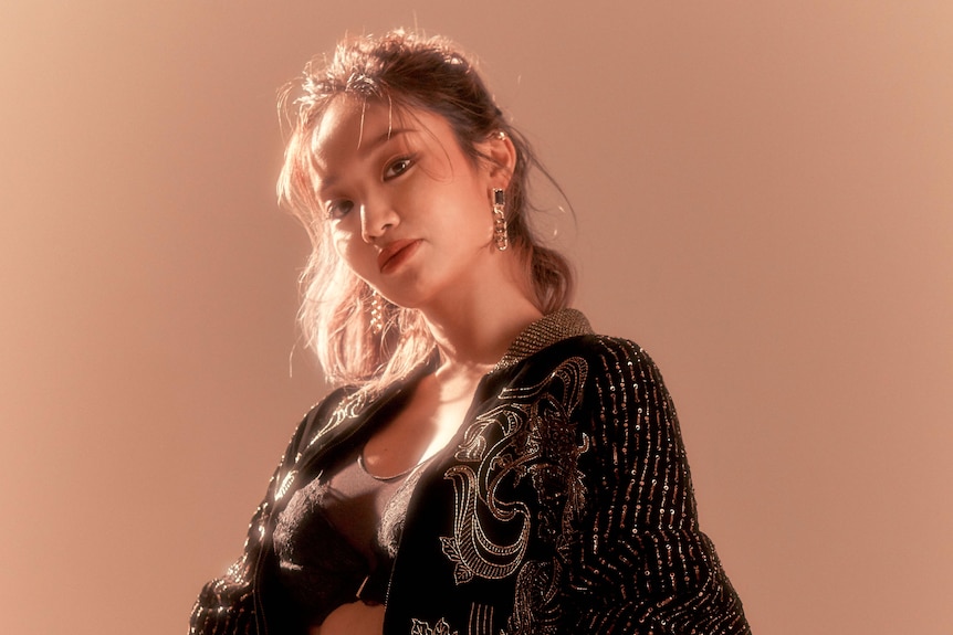 A woman poses to camera in a studio.