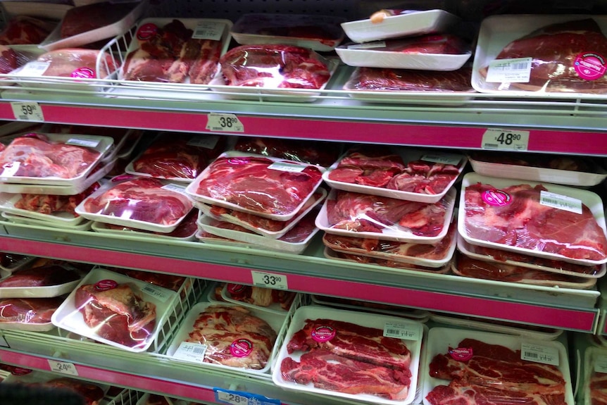 A supermarket fridge lined with trays of red meat.