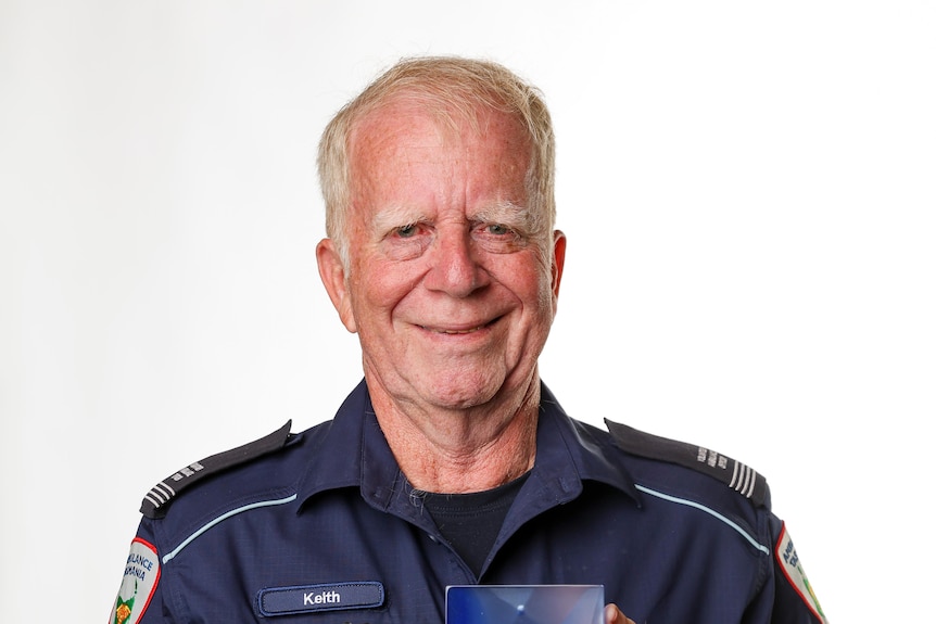A man wearing a paramedic uniform smiles.