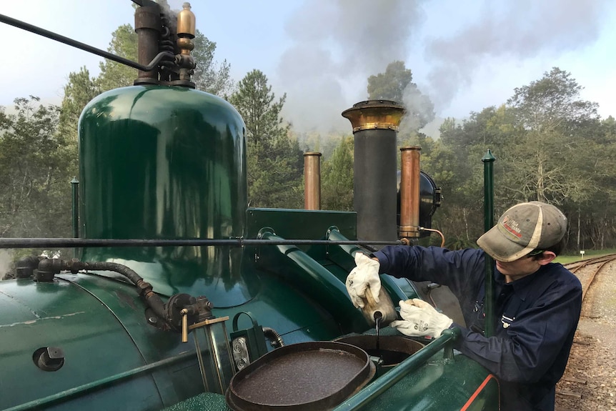Brock adds oil into the train on its 35 km journey on the vintage rail line linking Queenstown to Strahan
