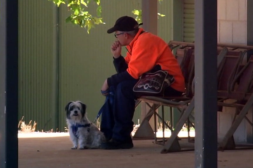 A man sits with this dog outside.