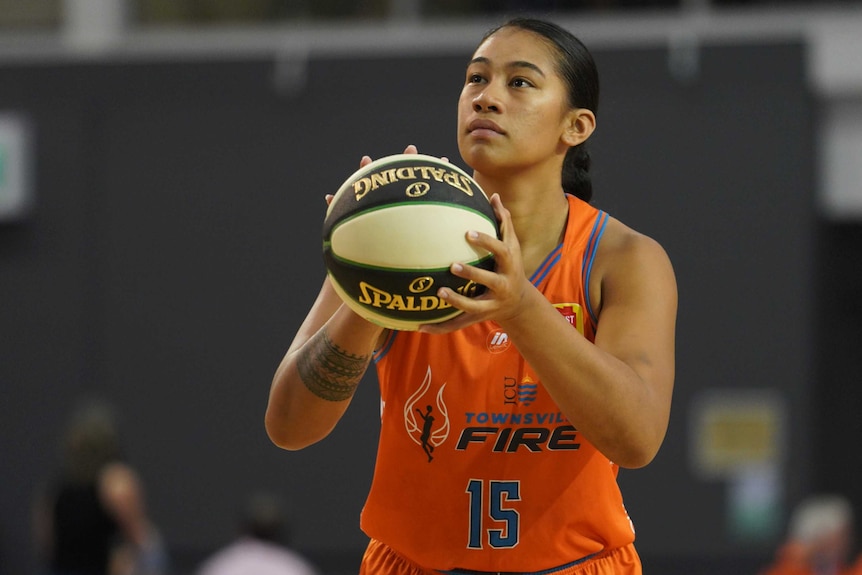 A Townsville Fire WNBL player holds the basketball as she prepares to shoot for the hoop.