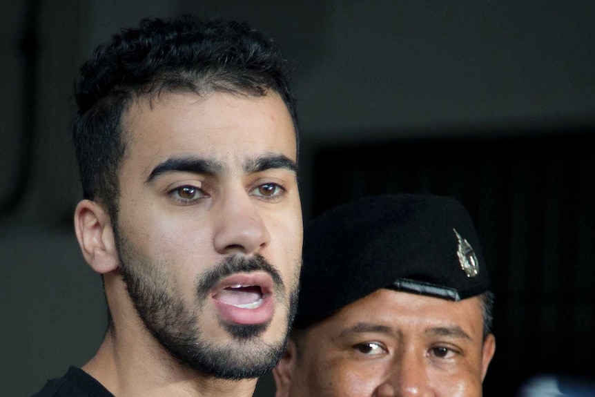 Bahraini football player Hakeem al-Araibi enters court as two policemen stand next to him