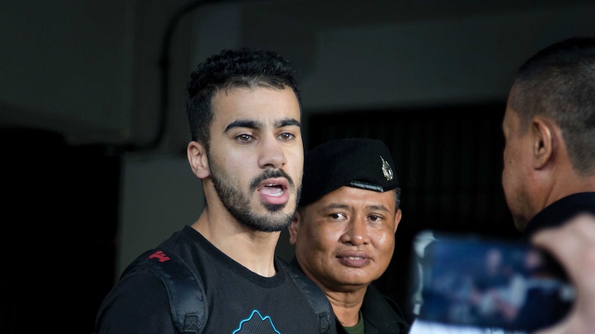 Bahraini football player Hakeem al-Araibi enters court as two policemen stand next to him