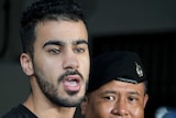 Bahraini football player Hakeem al-Araibi enters court as two policemen stand next to him