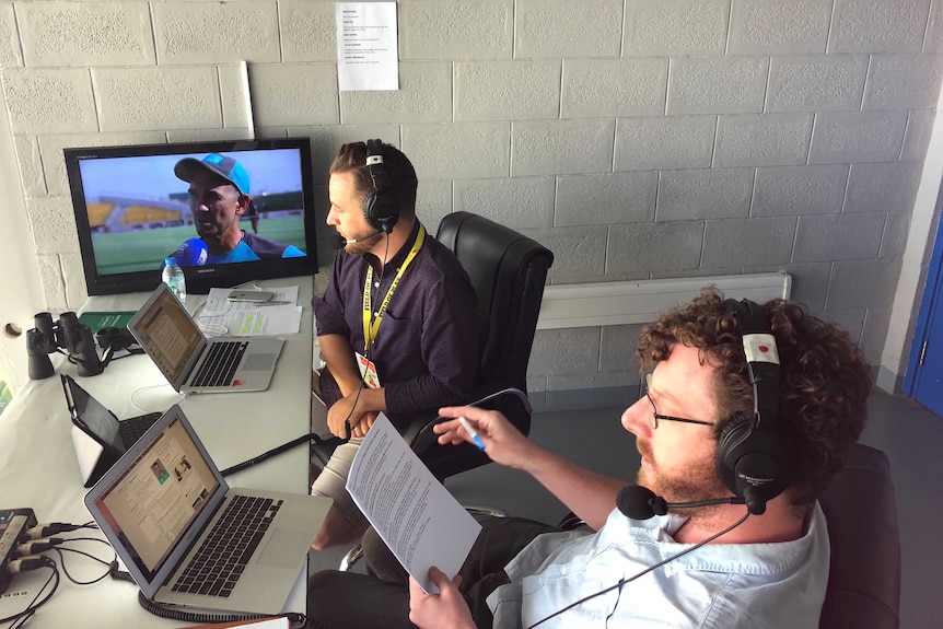 Tight shot of two commentators watching a match.