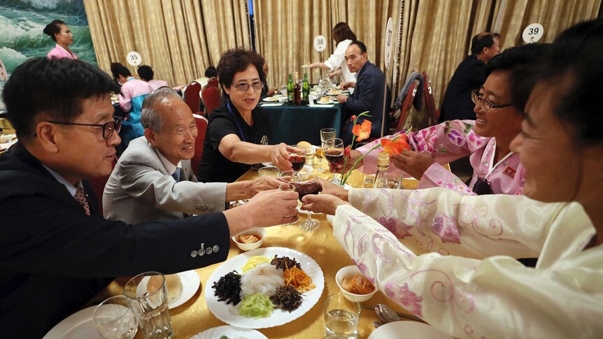North and South Korean family members toast at a table.