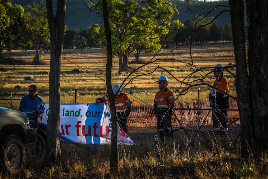 Workers stand near a sign erected by a protest group near the controversial Maules Creek coal mine project in NSW.