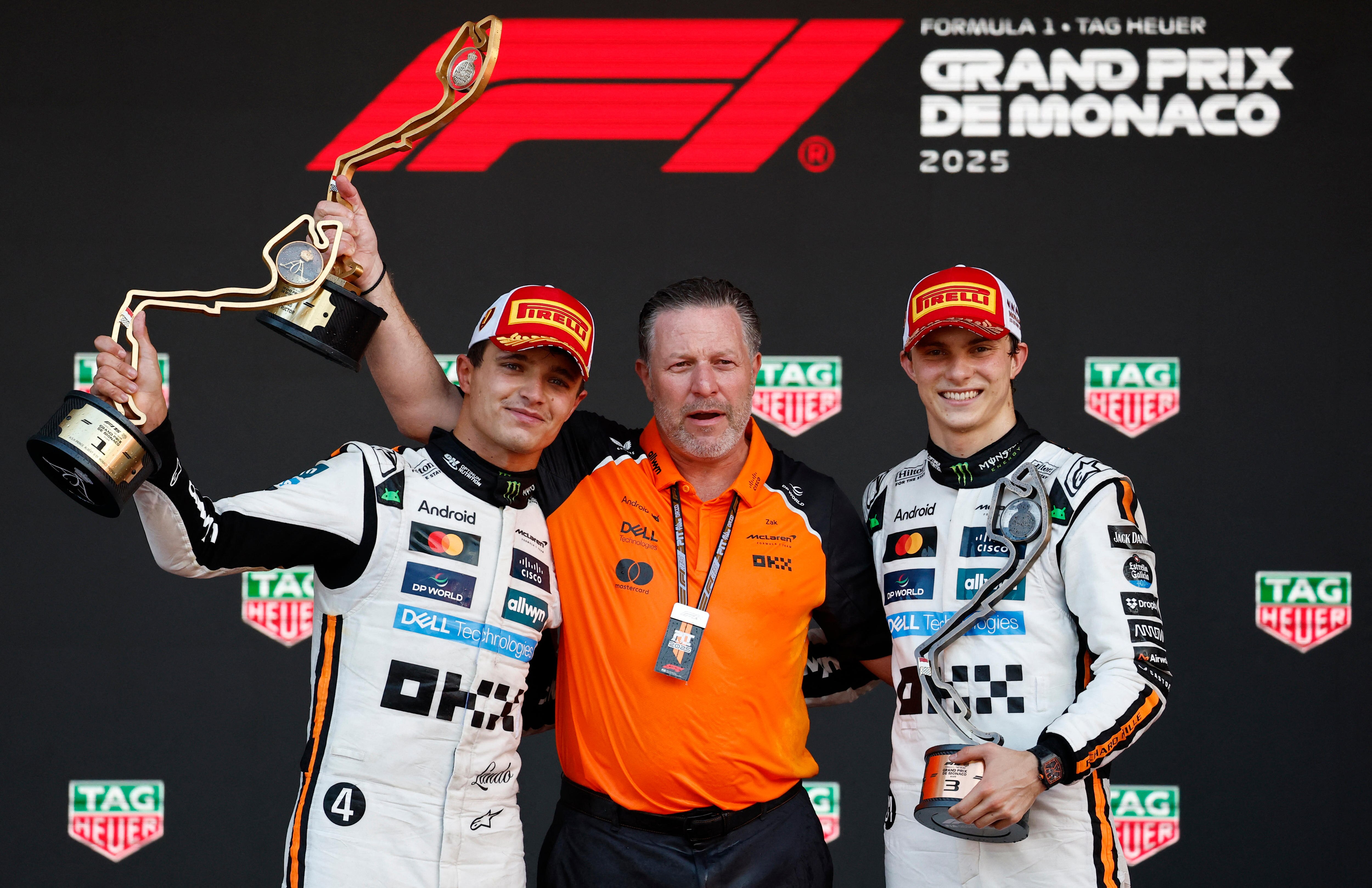 Two drivers and the team principal celebrate on the F1 podium